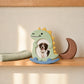 Green dinosaur rocking photo frame displayed on wooden shelf
