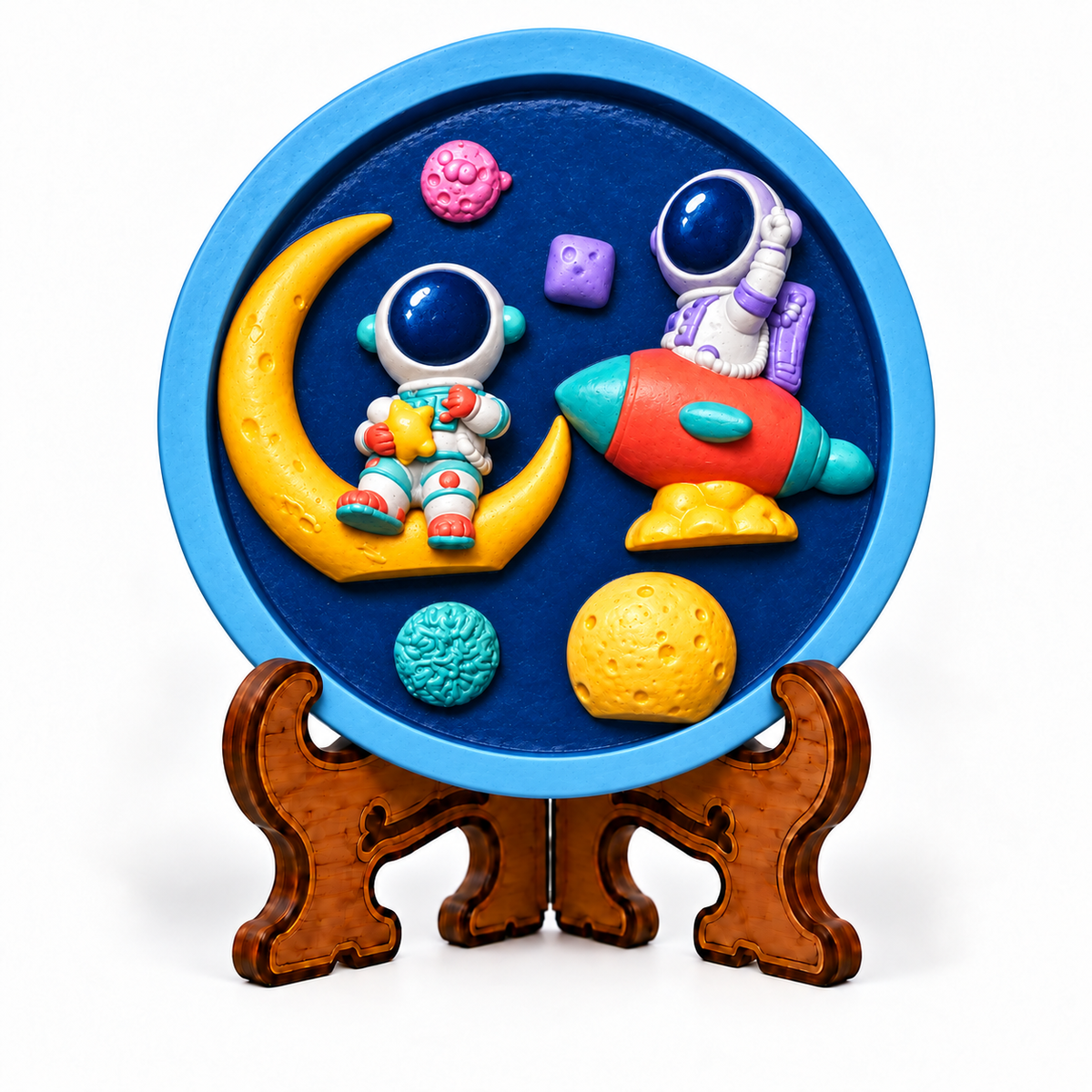 Colourful space-themed DIY craft plaque featuring two astronauts, a rocket, crescent moon and planets on a round display stand.