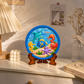 Round DIY ocean painting craft featuring colourful dolphin, fish, seahorse, octopus, crab and underwater scene on a display stand.