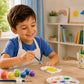 Child painting a white dinosaur craft with colourful paints