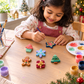 Child painting colourful Christmas DIY craft magnets with brush and paints at home